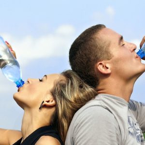 man and woman drinking from water bottles